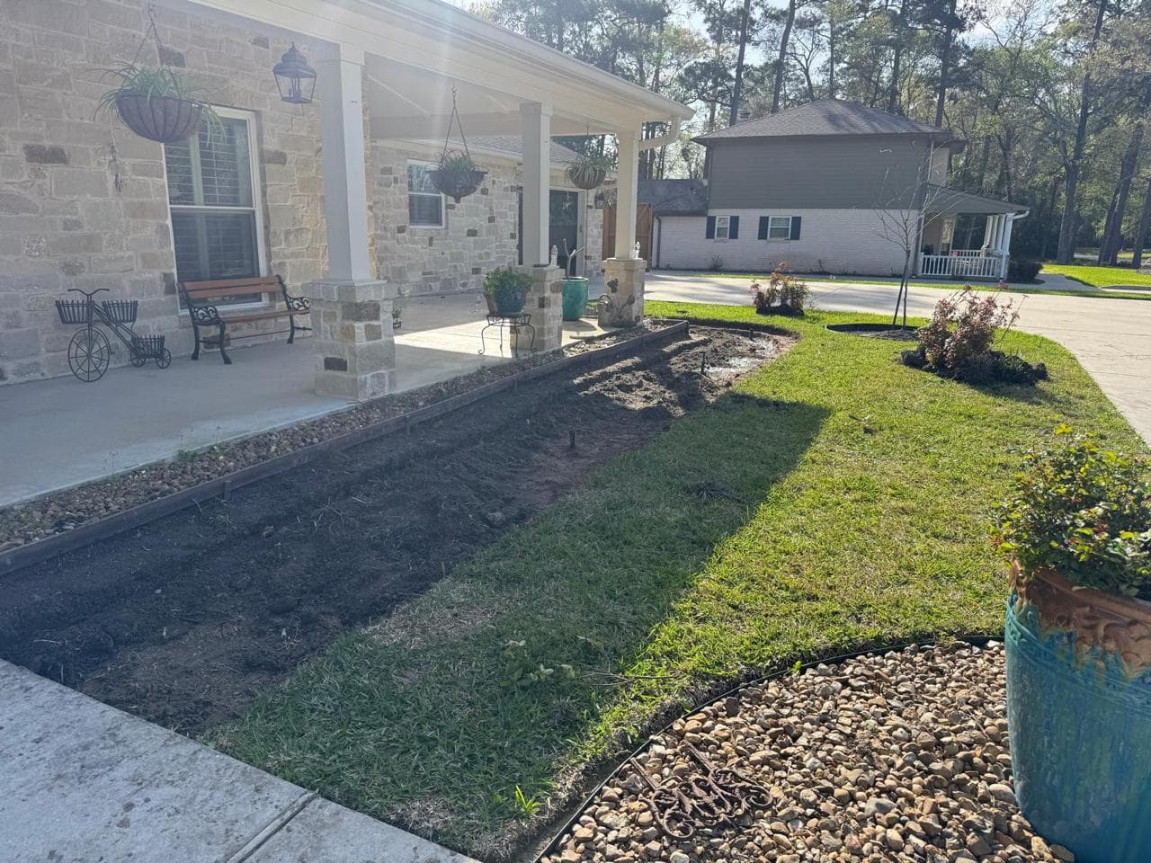 Fresh soil in a prepared planting bed running the length of a covered front entry